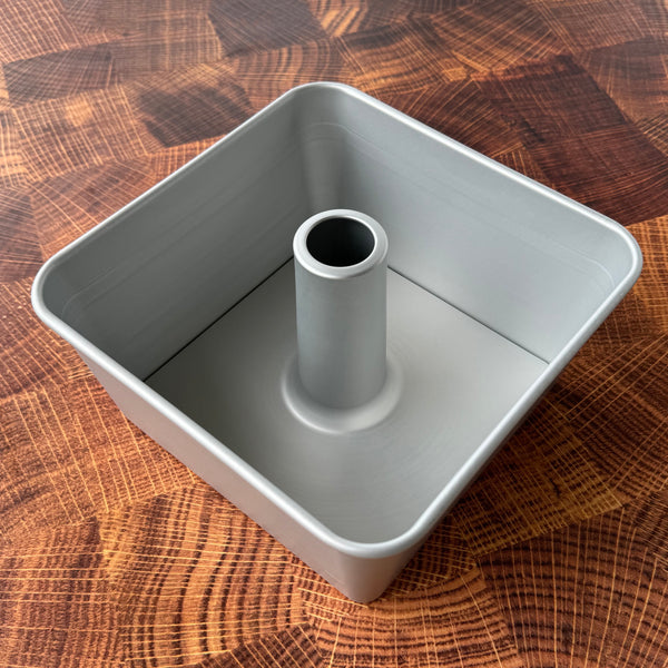 A two-piece square tube cake pan made of gray anodized aluminum, viewed from the top showing the 18 cup capacity and central tube.